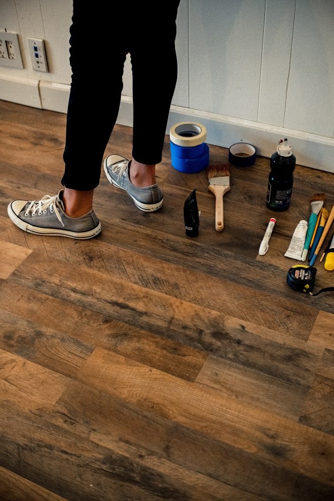 Person standing in a house with home improvement tools laying about the floor.