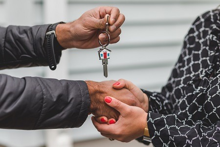 Persons hands shaking and handing house keys to each other.