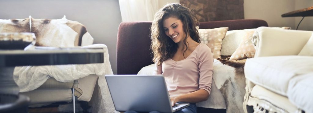 Person sitting on the floor of a living room working o a computer.