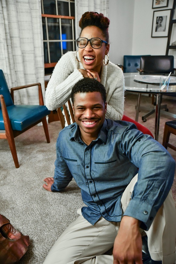 Two happy people sitting on the floor of their home smiling and laughing.