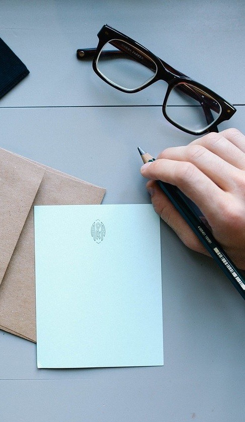 A person preparing to write a letter to a real estate seller on paper.