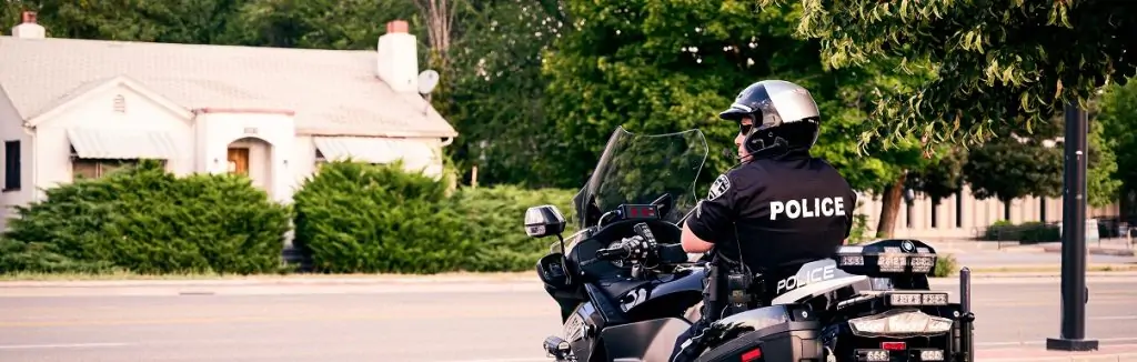 A police officer monitoring traffic in a residential area with a house in the background.