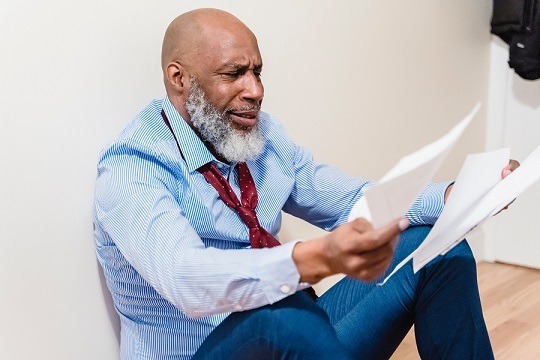 Person sitting on the floor looking at distressing paperwork.