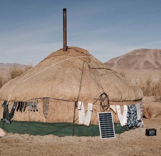 Image of a grass hut in the desert with solar panels.