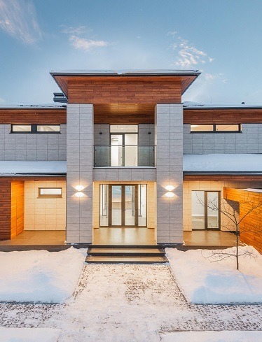 Image of the outside of a house with blue skies in the background and a light snow in the foreground