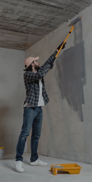 Person painting the wall of an unfinished house