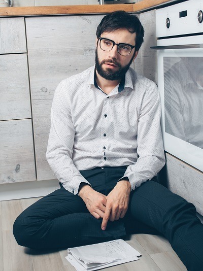 Person, looking sad, sitting on a floor pointing to a letter in an envelope.
