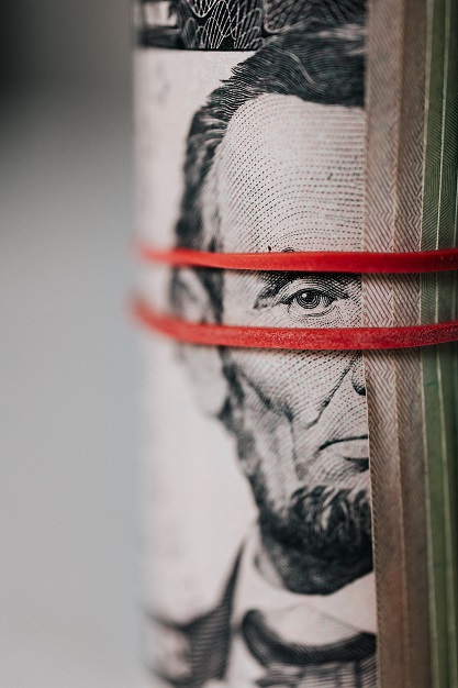 Image of rolled up currency wrapped with a red rubber band.