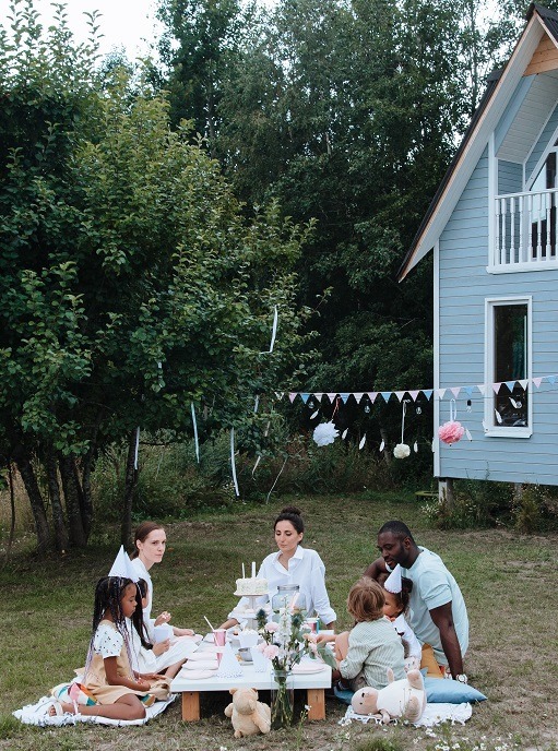 Family having a picnic in the yard outside their house.