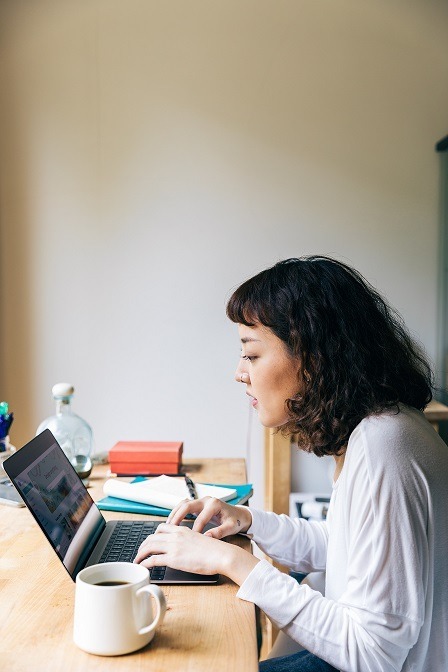Person looking at a computer sitting on a desk next to a cup of coffee.