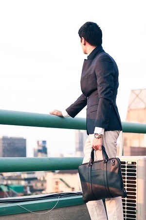 Person outside standing near a fence rail gazing over a bury city.